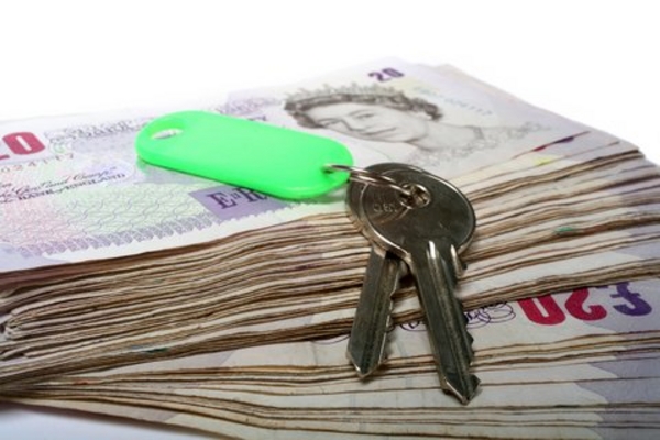 Stack of £20 notes with a set of keys resting on top with a green key fob.