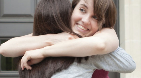 Female landlord and female tenant hugging with a smile, illustrating they are both happy with renting out a house.