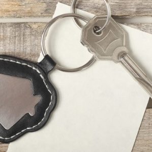 Key with fob on top of piece of paper on a wooden table.